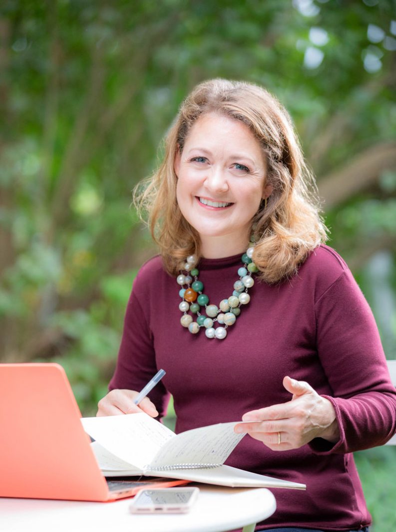 Rhonda Schlangen working at a table, smiling at the camera